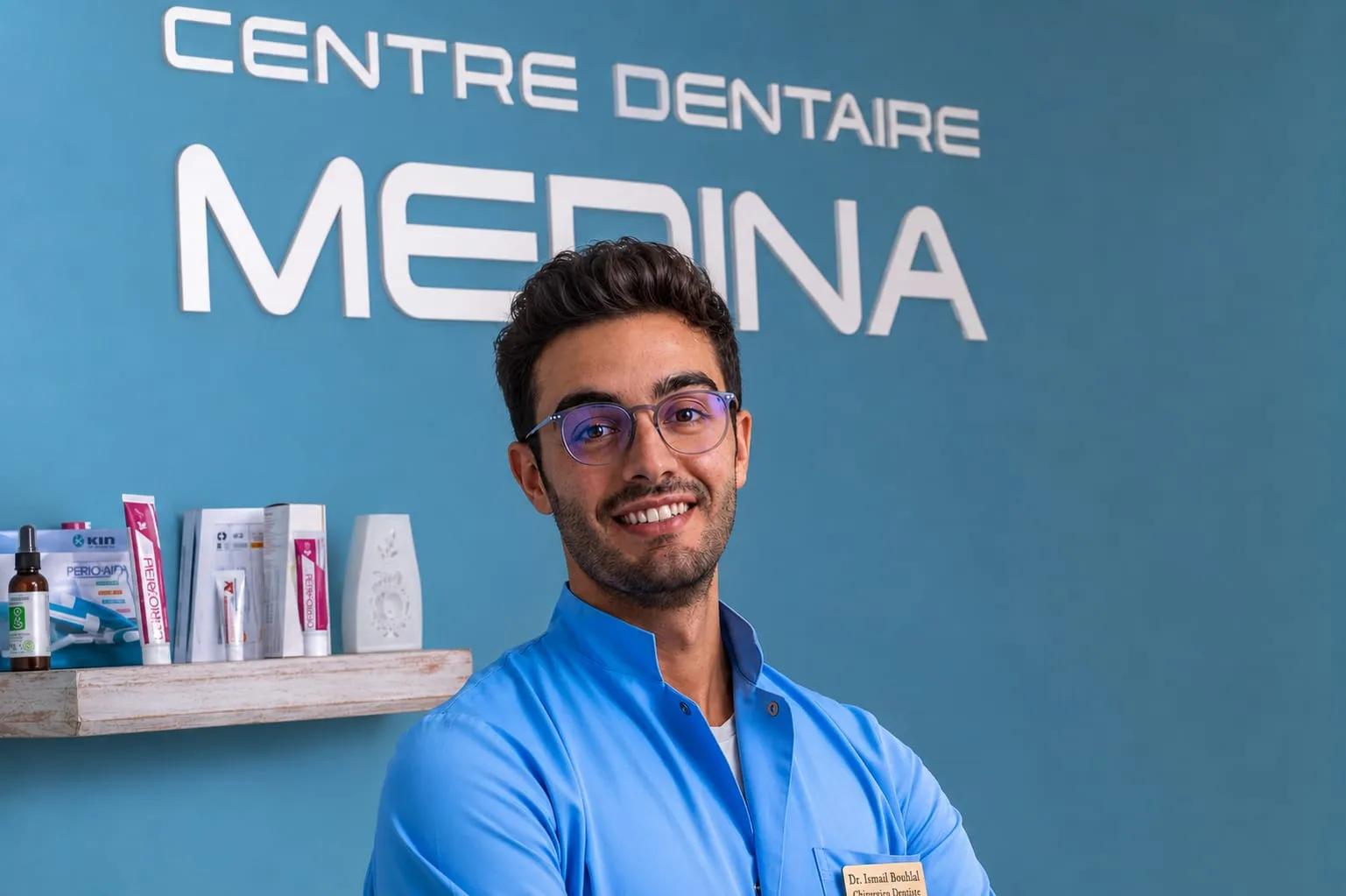 Le Dr. Ismail Bouhlal, souriant, devant le logo du Centre Dentaire Medina à Tanger